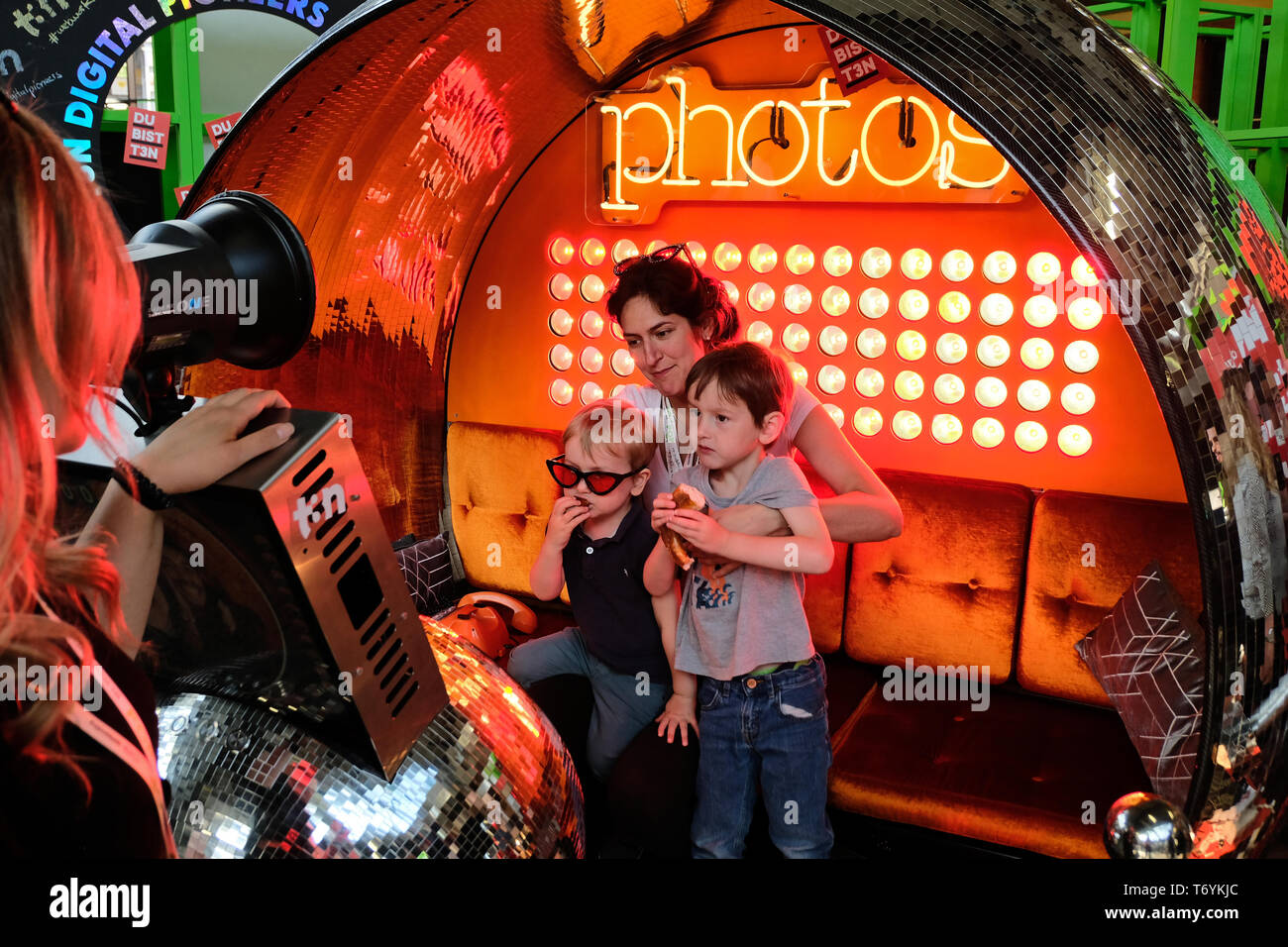 Berlin, Germany - May 3, 2018: Employee of the t3n computer magazin takes a promo photo at their booth of a visitor family. re:publica is a conference Stock Photo