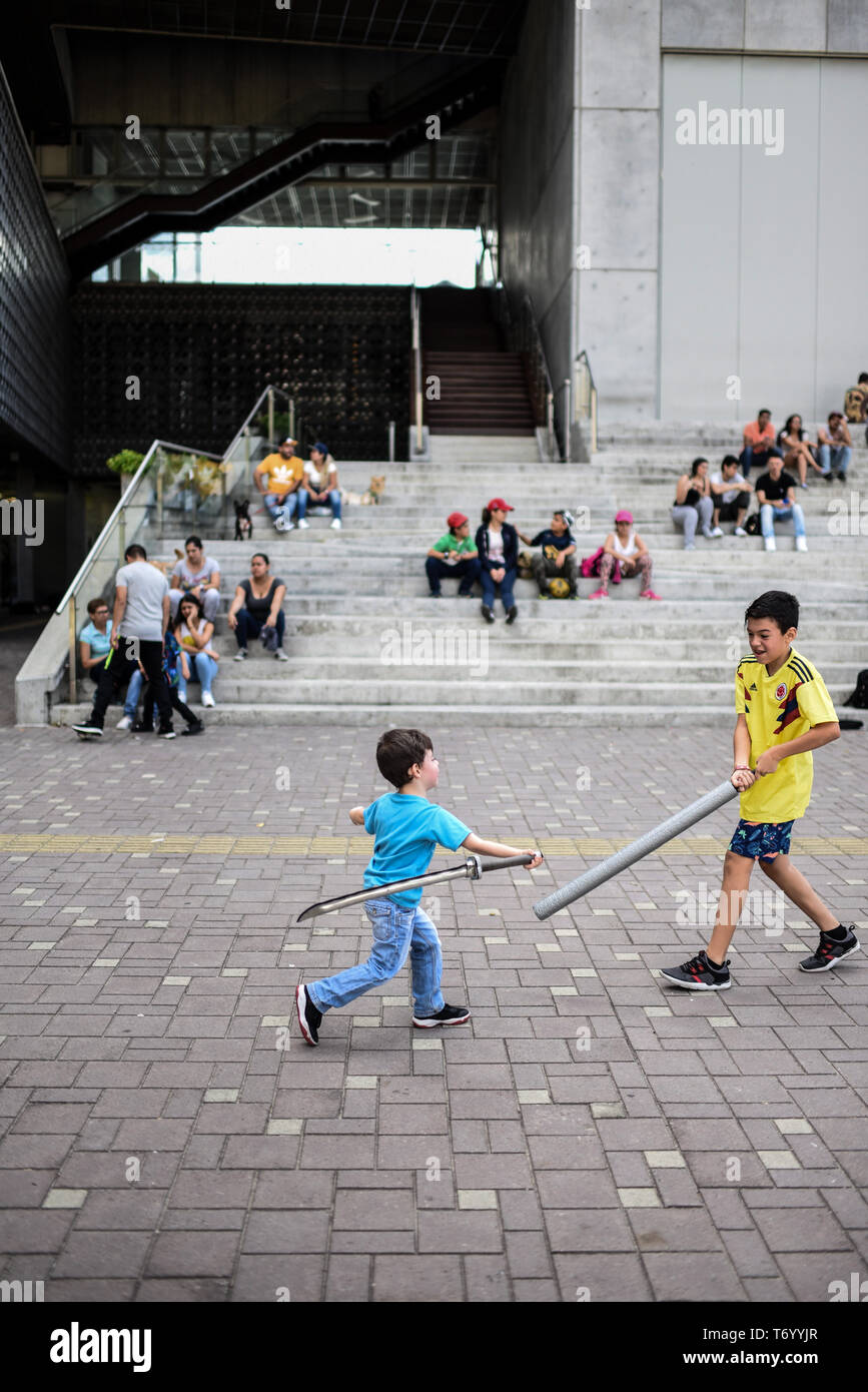 Kids fight with plastic swords outside The Museum of Modern Art of Medellin (MAMM), Colombia Stock Photo