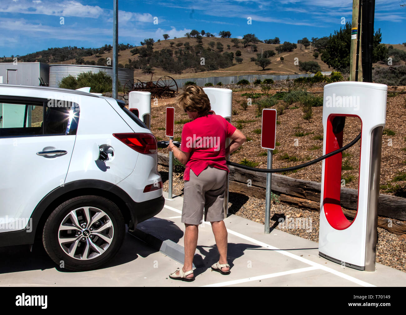 Woman motorist preparing to charge electric vehicle battery at Gundagai in New South Wales, Australia Stock Photo