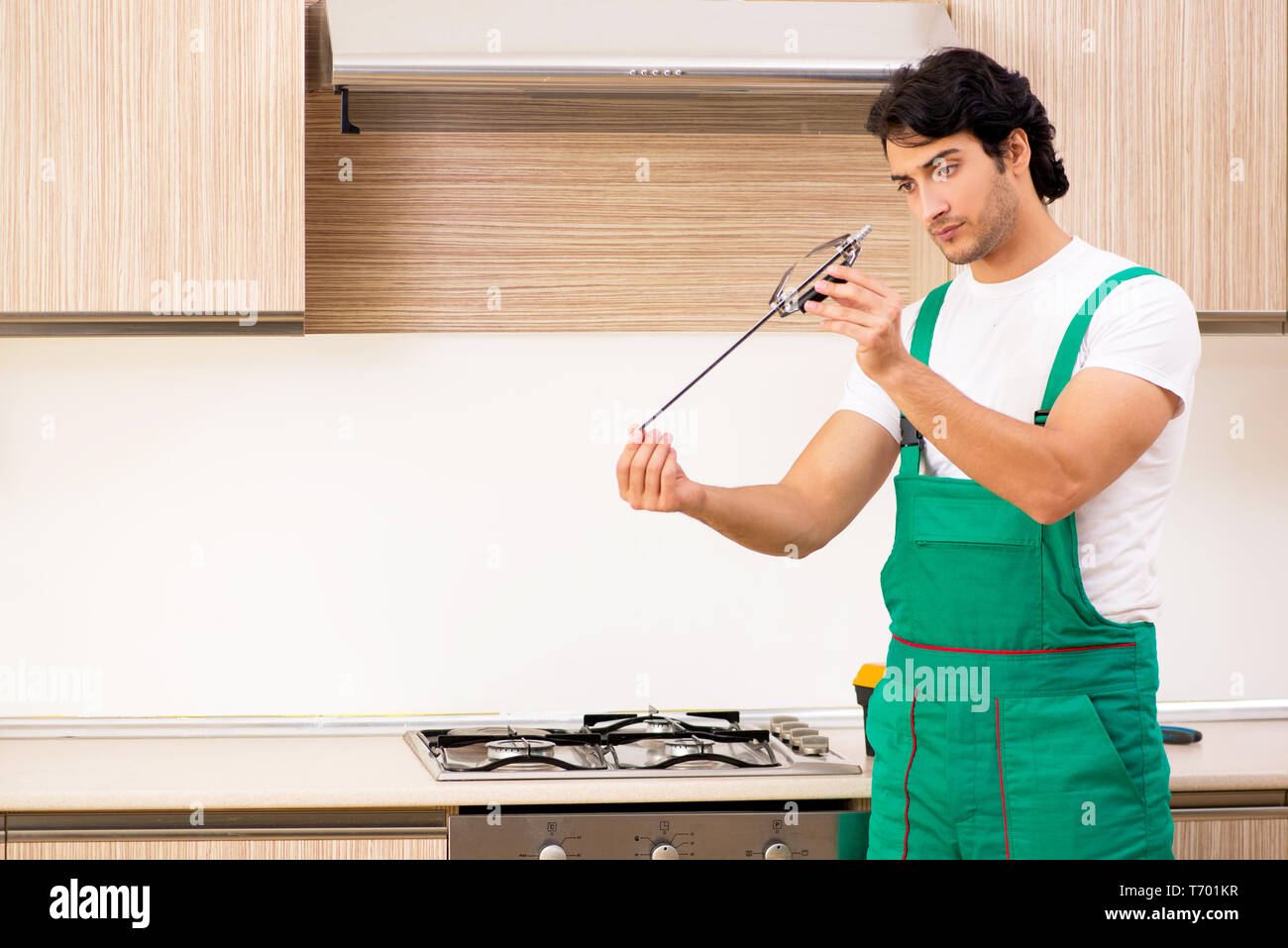 Young contractor repairing oven in kitchen Stock Photo