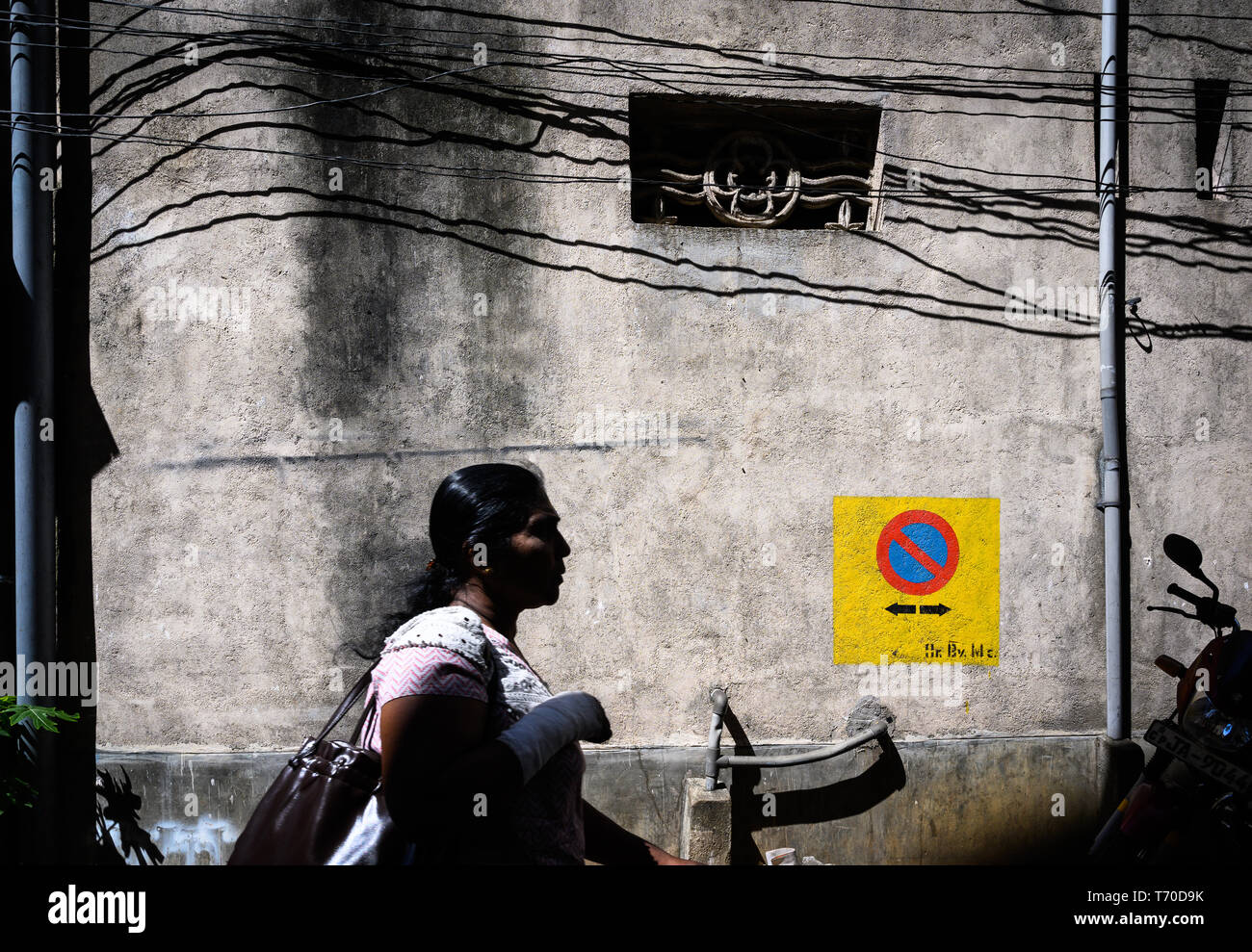 Pedestrian passing a wall with electrical wires, Kandy, Sri Lanka Stock Photo