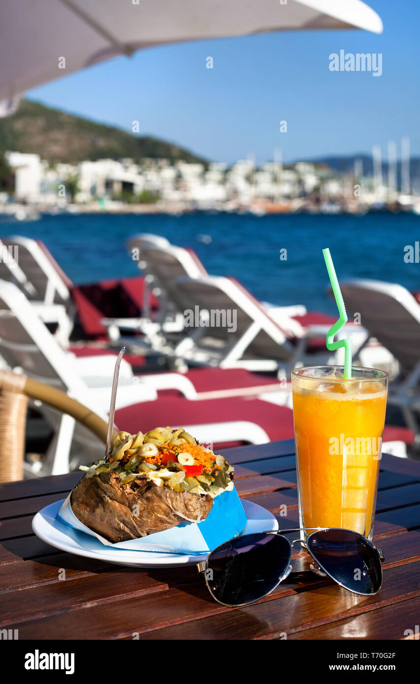 Stuffed potato with vegetables called Kumpir and Orange juice in sea view resort in South of Turkey Stock Photo