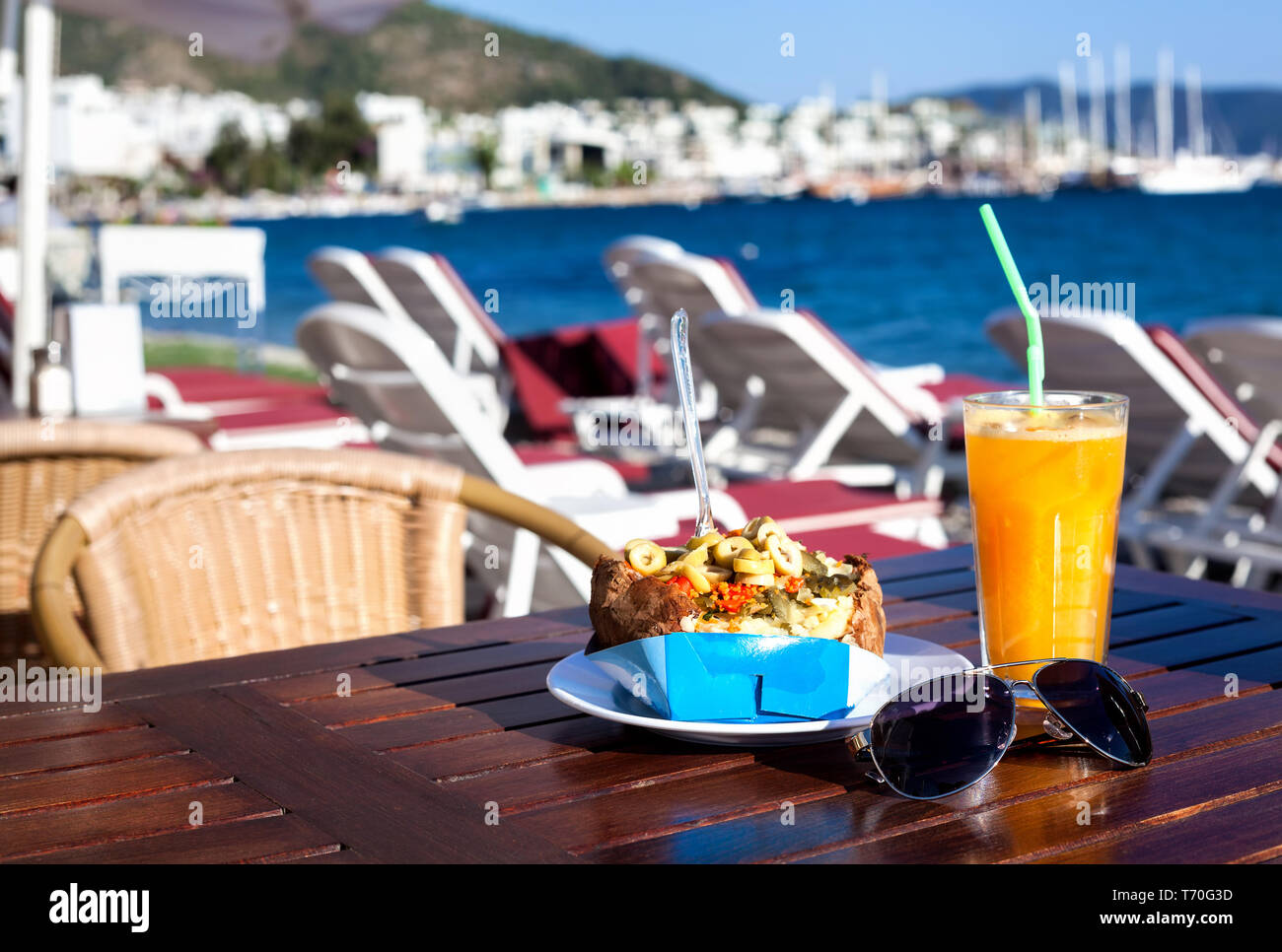 Stuffed potato with vegetables called Kumpir and Orange juice in sea view resort in South of Turke Stock Photo