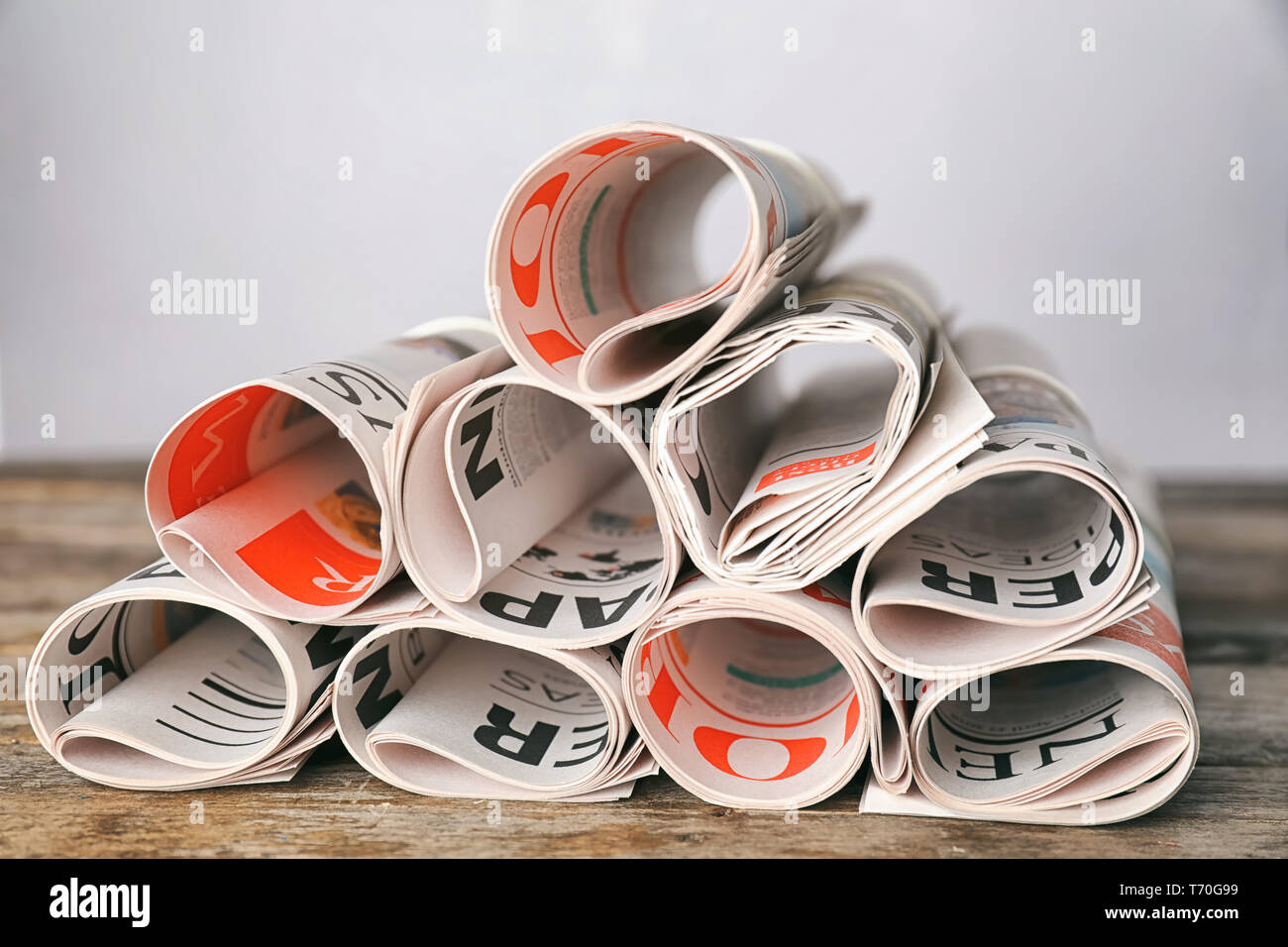 Rolled newspapers on wooden table Stock Photo