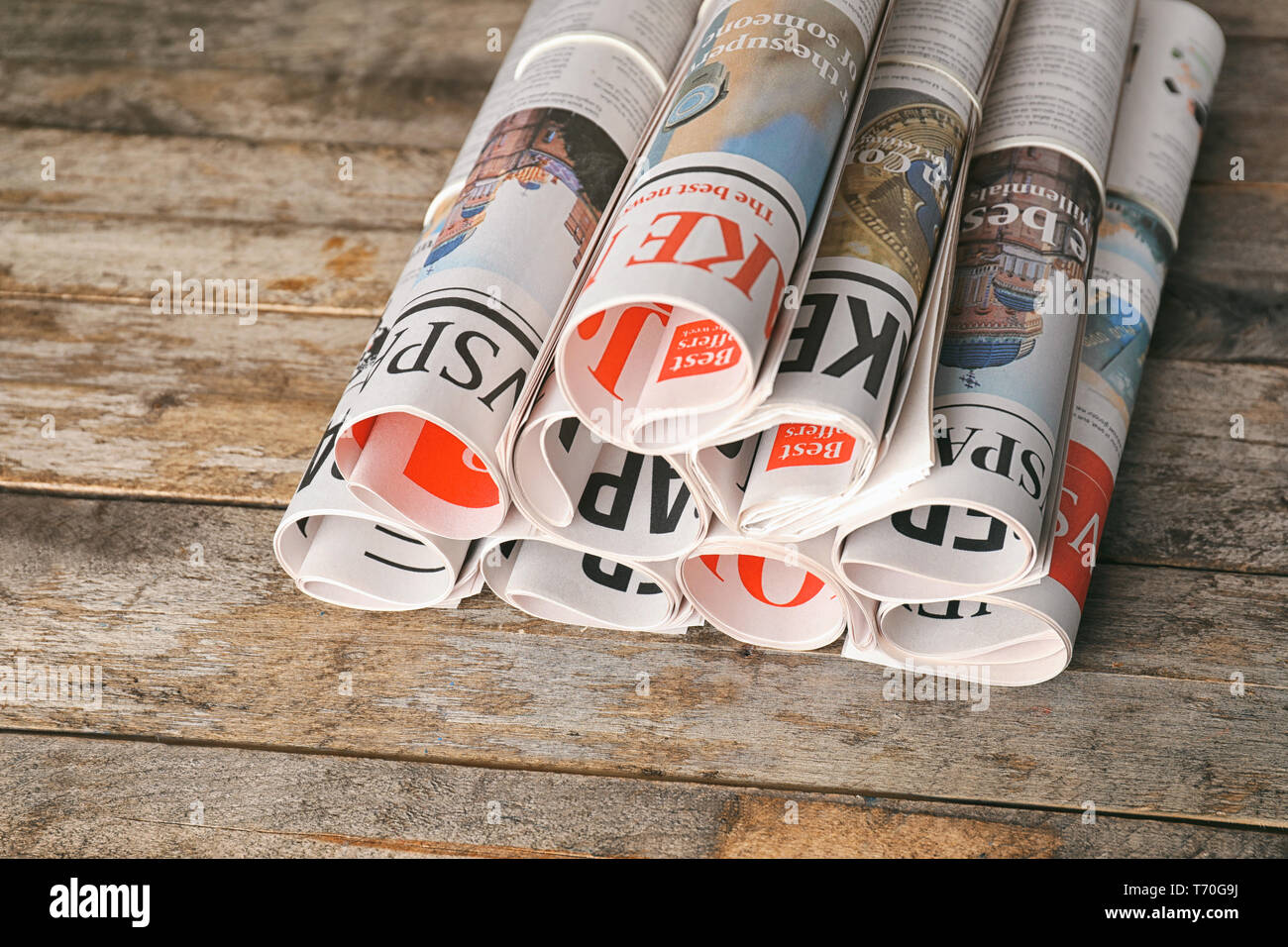 Rolled newspapers on wooden background Stock Photo