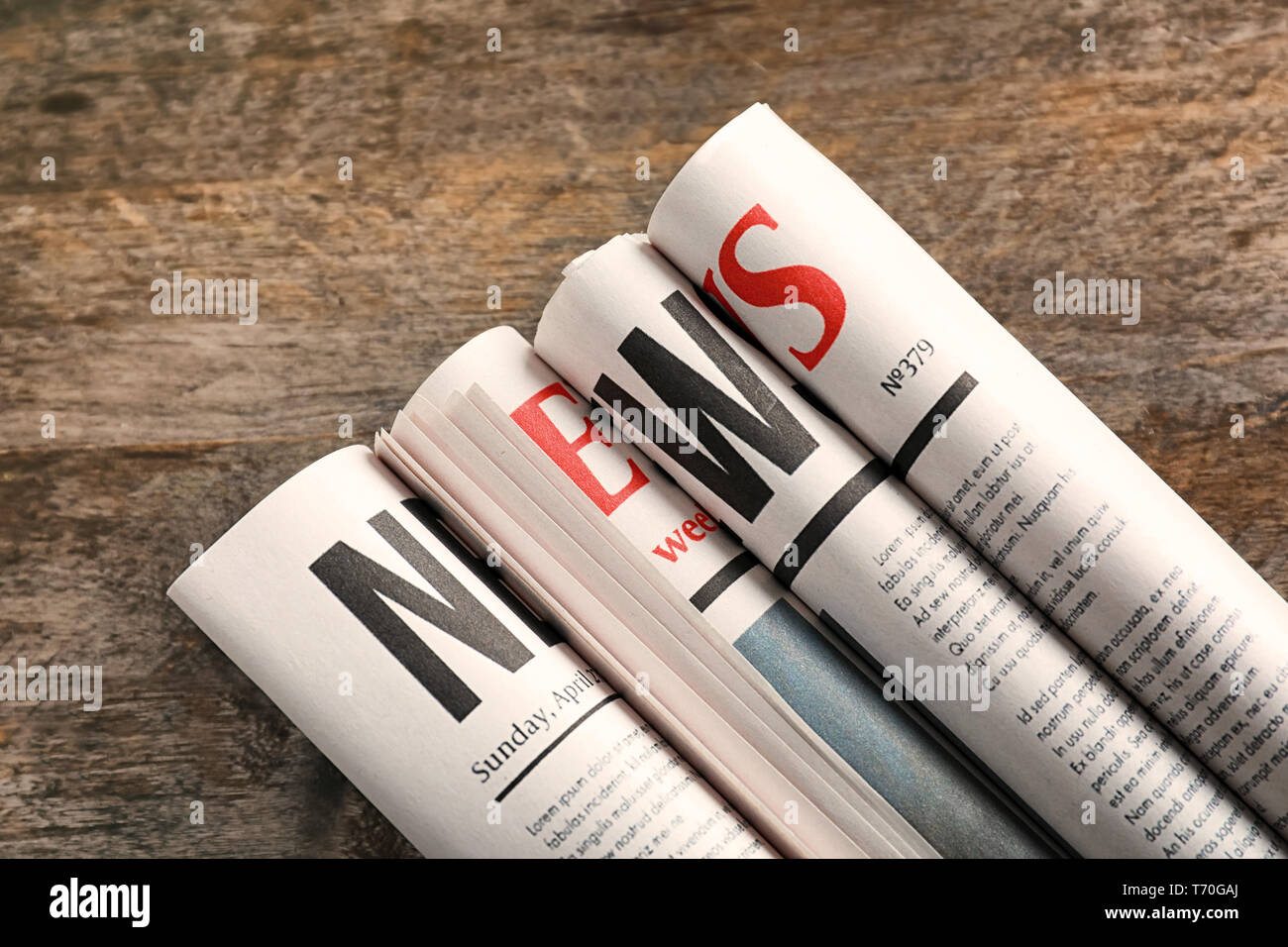 Rolled newspapers on wooden background Stock Photo