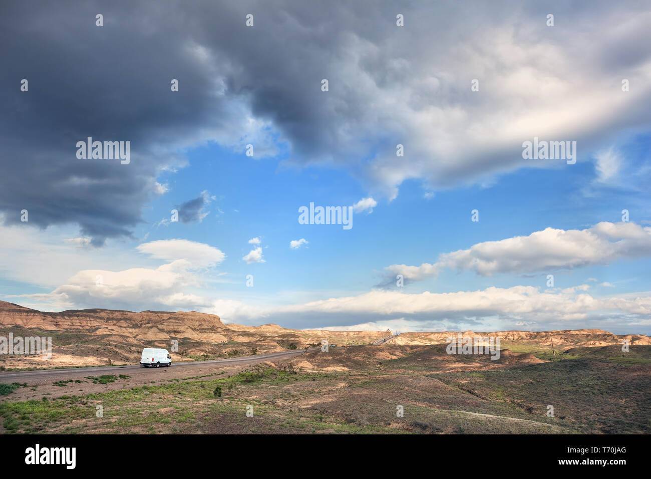 White van at highway road in the desert and cloudy blue sky Stock Photo