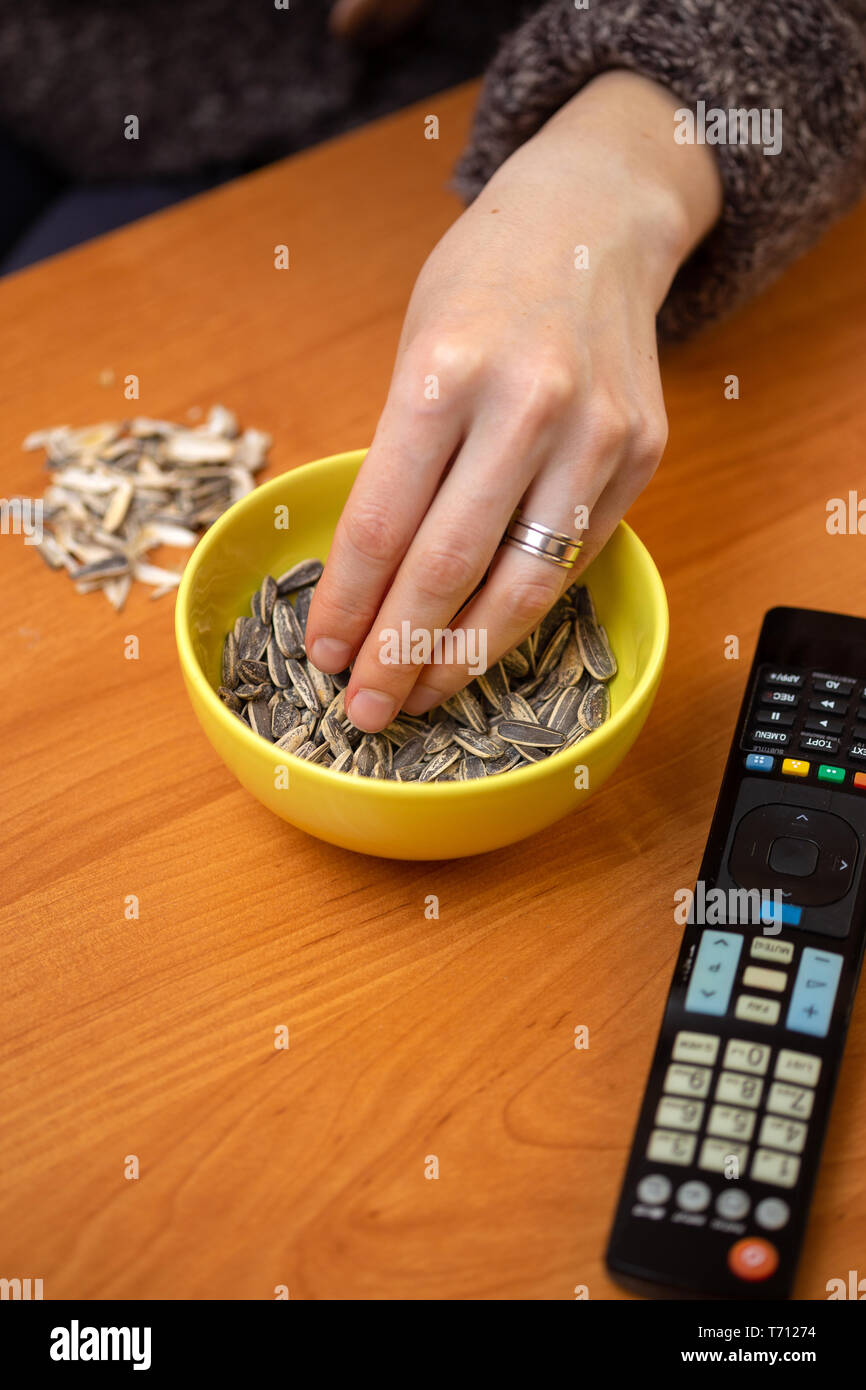 People eating roasted sunflower seed and watch a tv with copy space Stock Photo