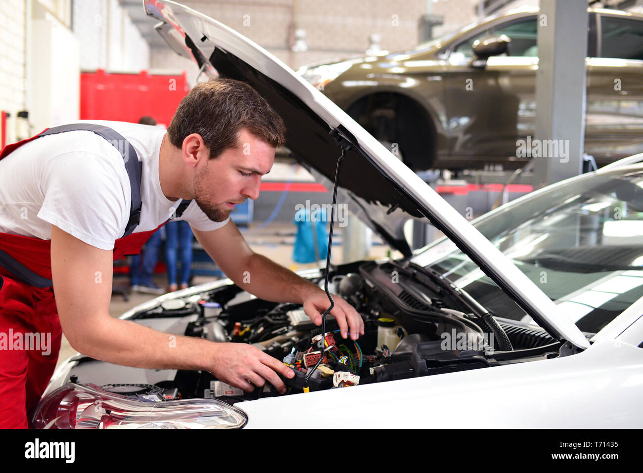 customer service in the garage - mechanic checks and repairs the engine of a car Stock Photo