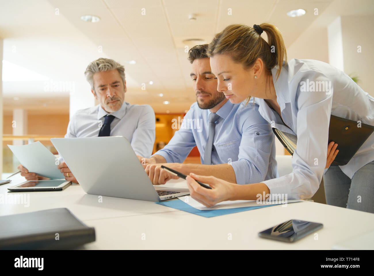 Group of startup coworkers looking at computer in office Stock Photo ...