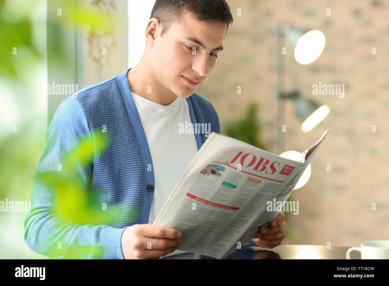 Handsome young man reading newspaper in cafe Stock Photo - Alamy