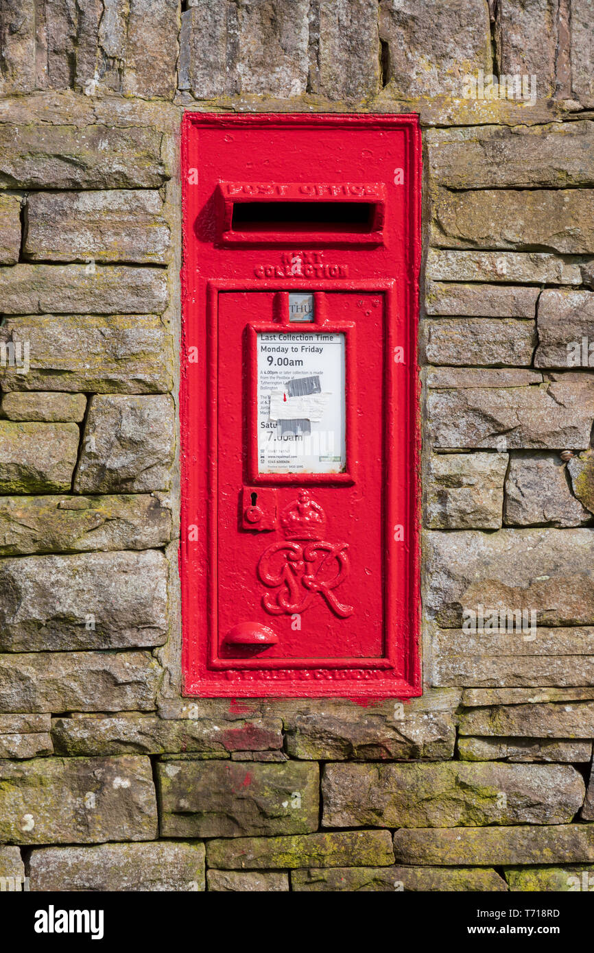 Postbox on a rural dry stone wall. The red post box is vertical formal Stock Photo