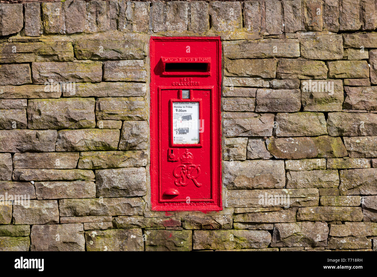 Red Royal Mail postbox on a rural dry stone wall. In portrait format Stock Photo