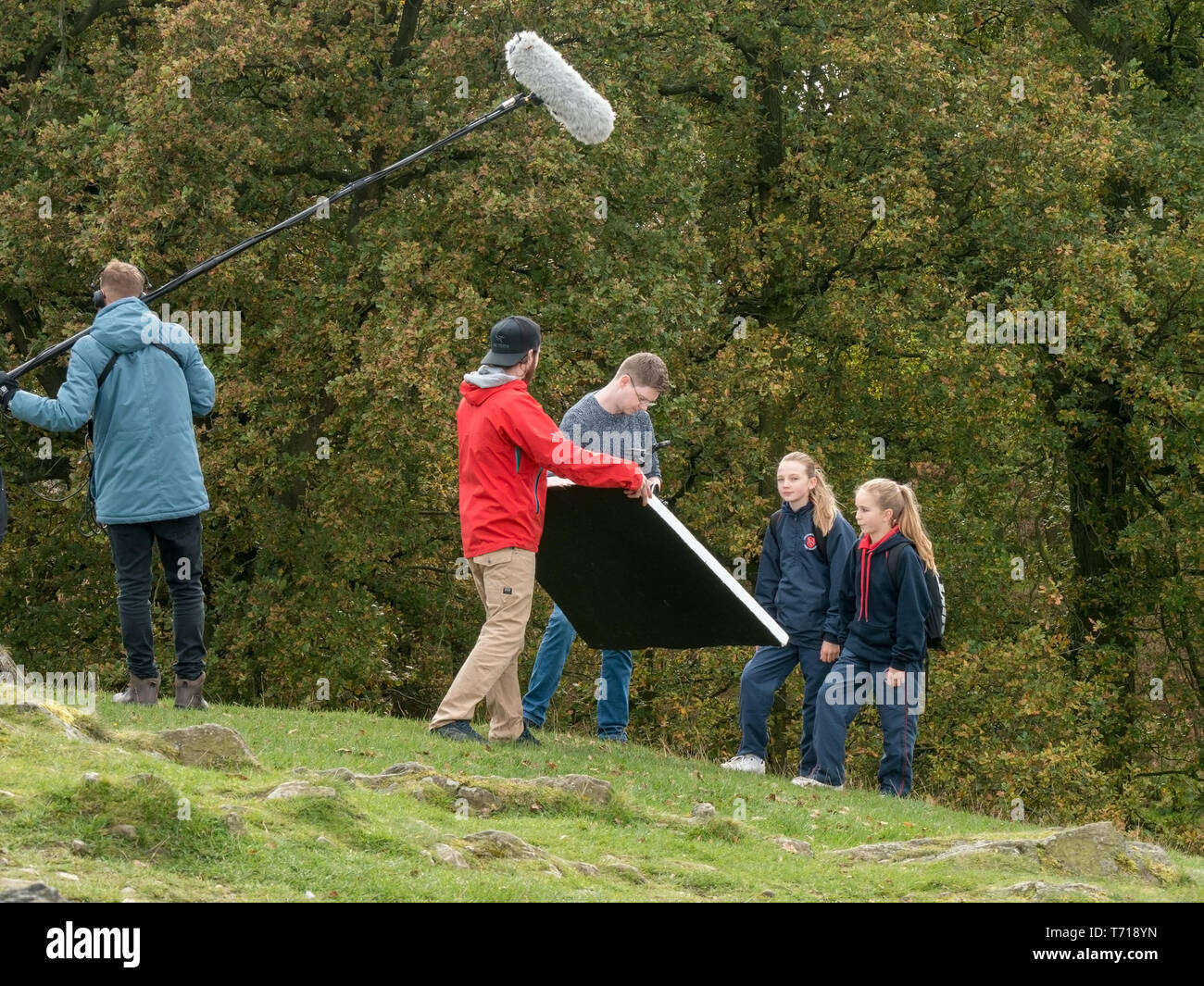 Students using light reflector and boom microphone whilst filming and sound recording young actors in Bradgate Park, Leicestershire, UK Stock Photo