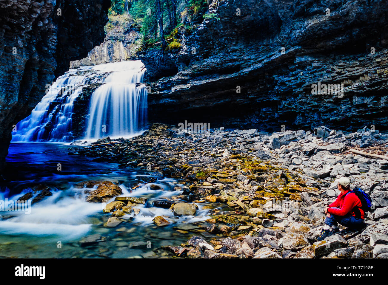 Woman sitting besides waterfall. Stock Photo