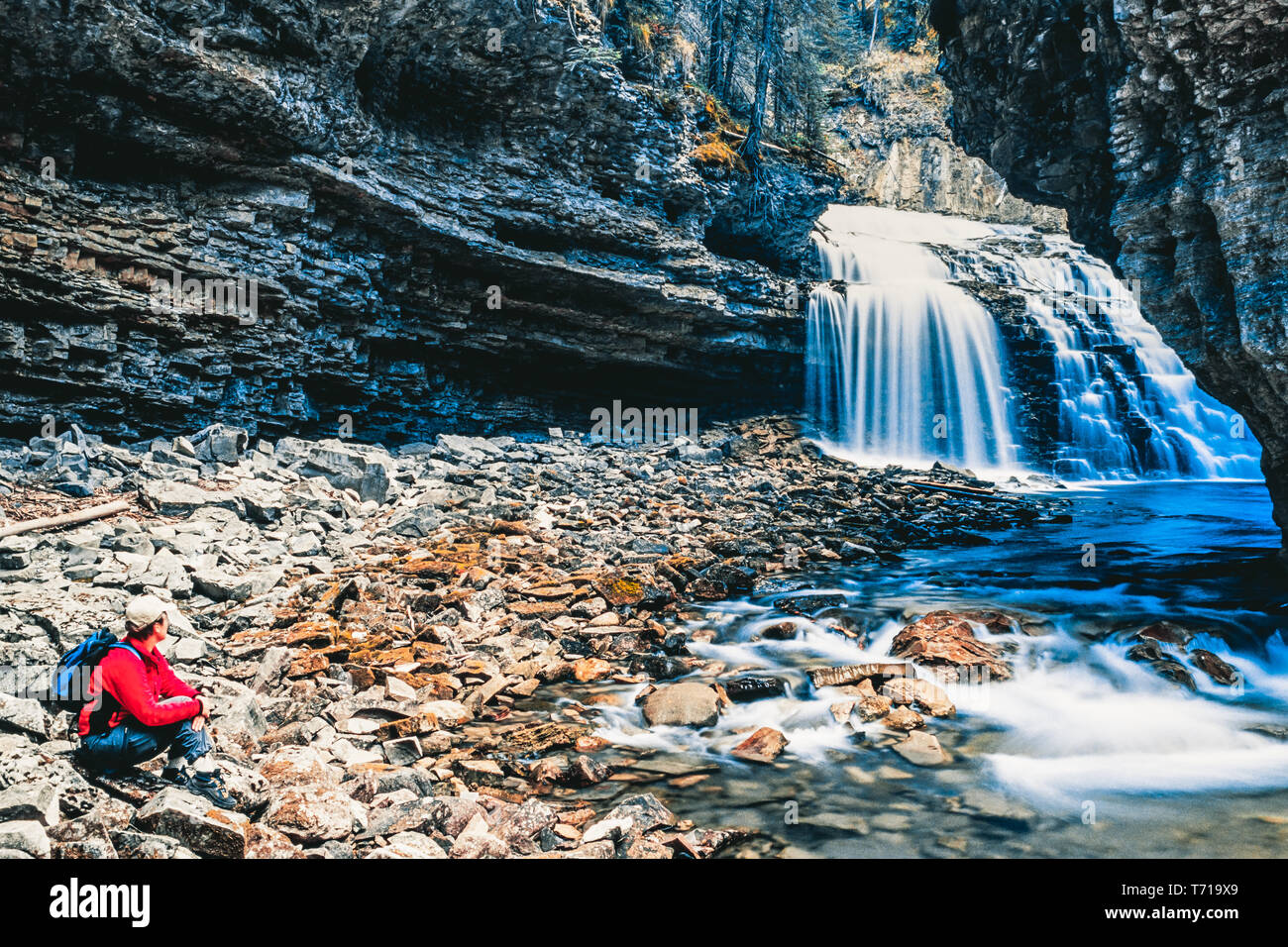 Woman sitting besides waterfall at Johnston Canyon. Banff Nationalpark, Canada. Stock Photo