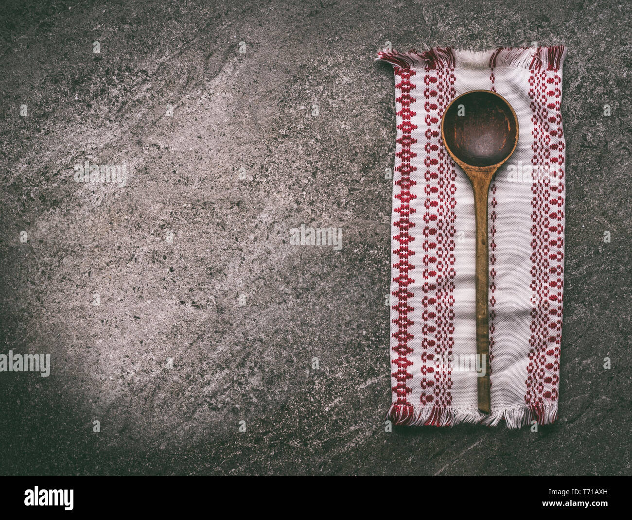 Aged wooden spoon with kitchen napkin on rustic stone kitchen table, top view. National cuisine food and cooking background. Copy space for your desig Stock Photo