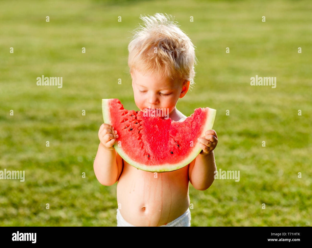 One year old baby boy eating watermelon in the garden Stock Photo