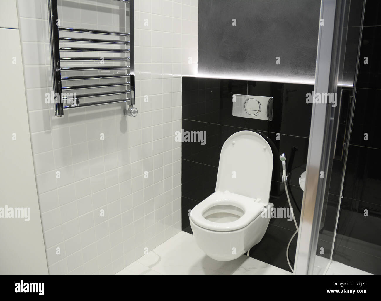 White toilet bowl with thermostatic electric towel rail for bathroom. Stock Photo