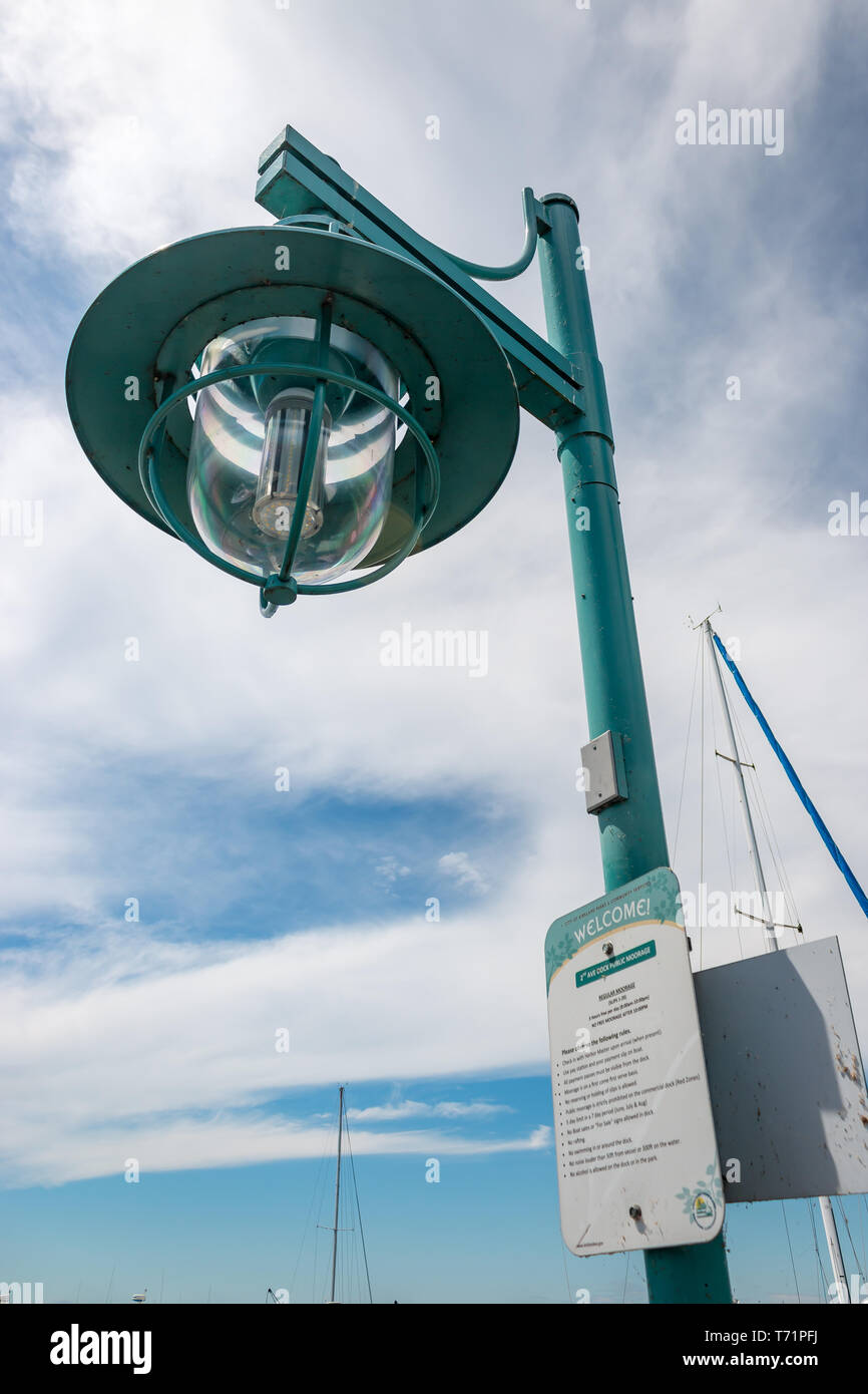 A green streetlight with a welcome sign towers over a dock at the marina in Kirkland, Washington. Stock Photo