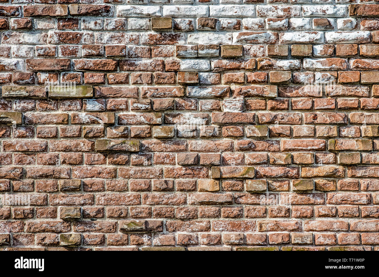Old masonry wall with chalk and other impurities and with protruding bricks forming an irregular relief pattern Stock Photo