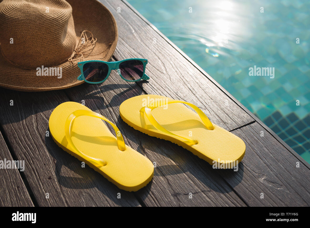 Hat, sunglasses and flip flops by swimming pool Stock Photo - Alamy