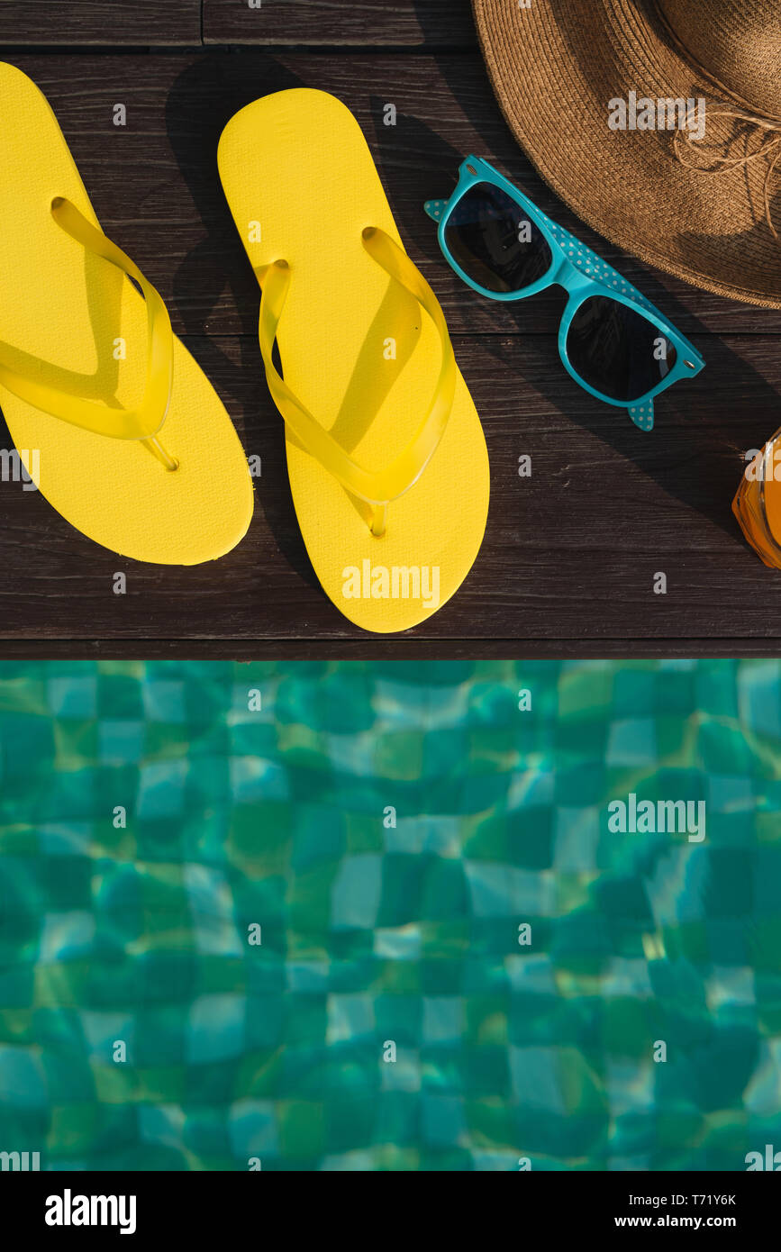 Hat, sunglasses and flip flops by swimming pool Stock Photo - Alamy