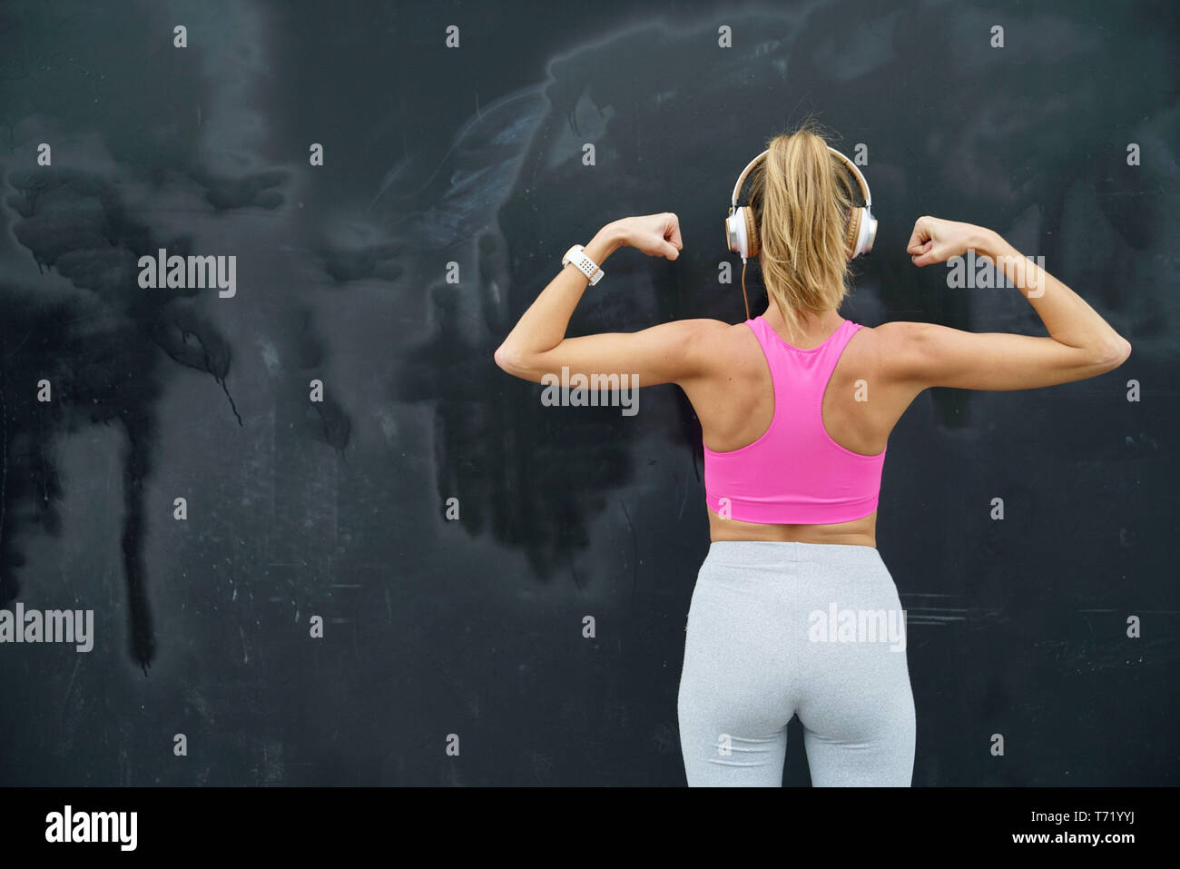 https://c8.alamy.com/comp/T71YYJ/back-of-strong-toned-woman-in-sportswear-and-headphones-on-black-background-T71YYJ.jpg