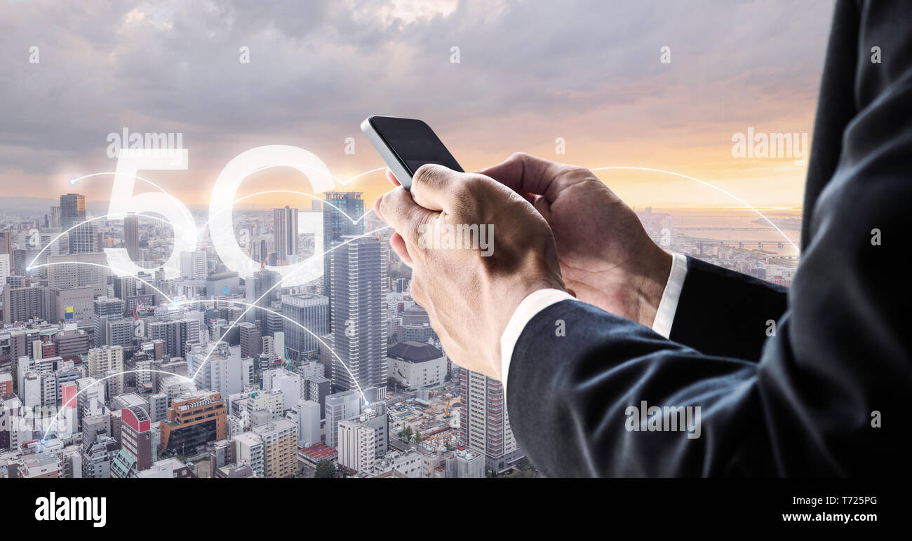 Internet networking and wireless technology. Businessman using mobile smart phone with city view in sunset, and 5G internet networking Stock Photo