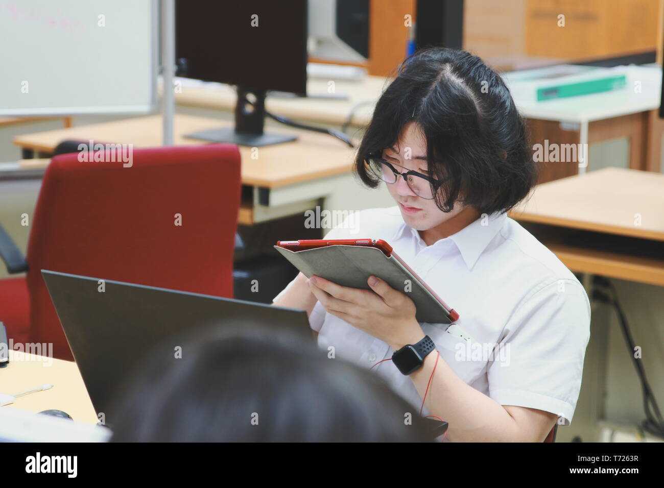 Chinese Computer Engineering Student taking lecture note on his iPad using Apple Pencil during a computer programming class Stock Photo