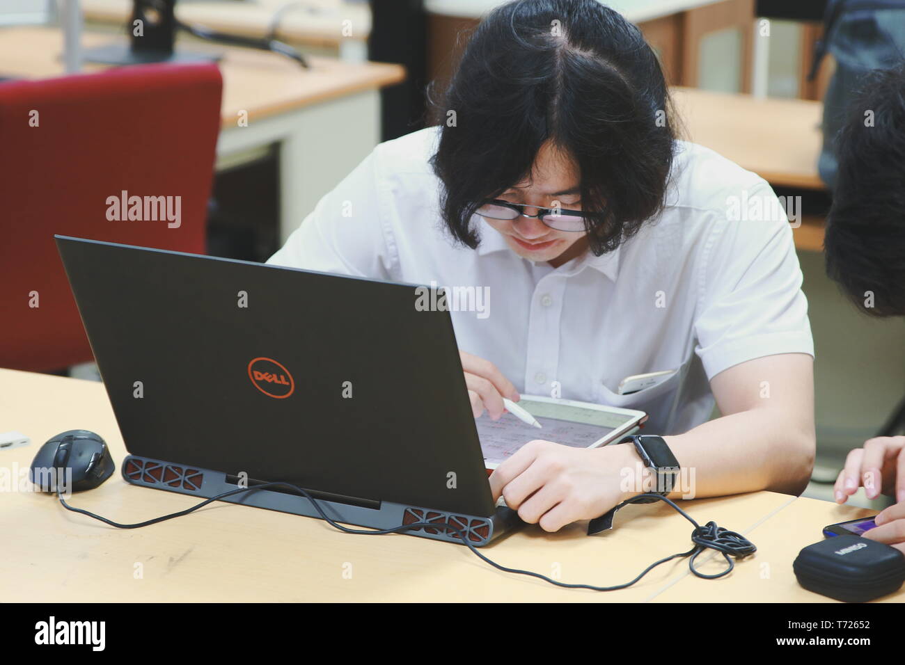 Chinese Computer Engineering Student taking lecture note on his iPad using Apple Pencil during a class Stock Photo