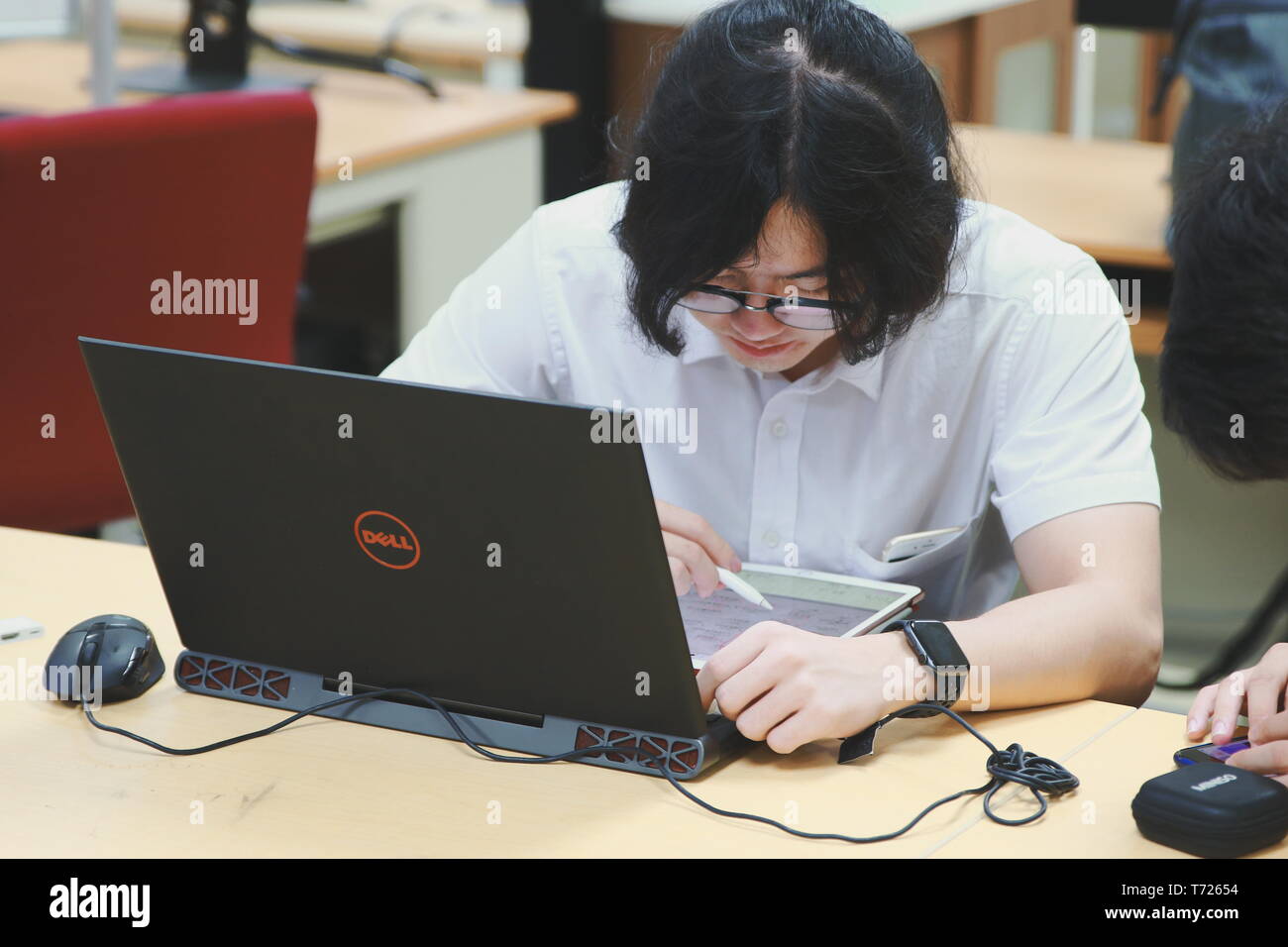 Chinese Computer Engineering Student taking lecture note on his iPad using Apple Pencil during a class Stock Photo