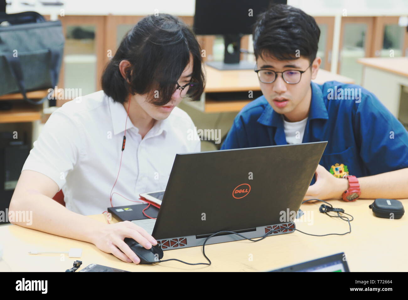 Two Chinese computer engineering student working together on a laptop in a computer programming class Stock Photo