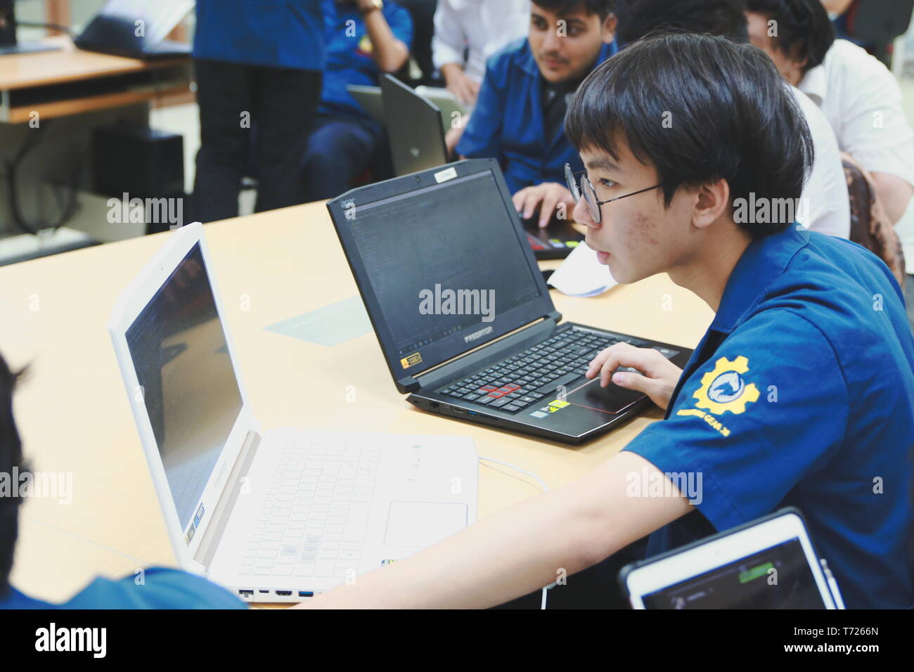 Portrait of a Computer Engineering student at Assumption University working on his coding project on two laptops Stock Photo