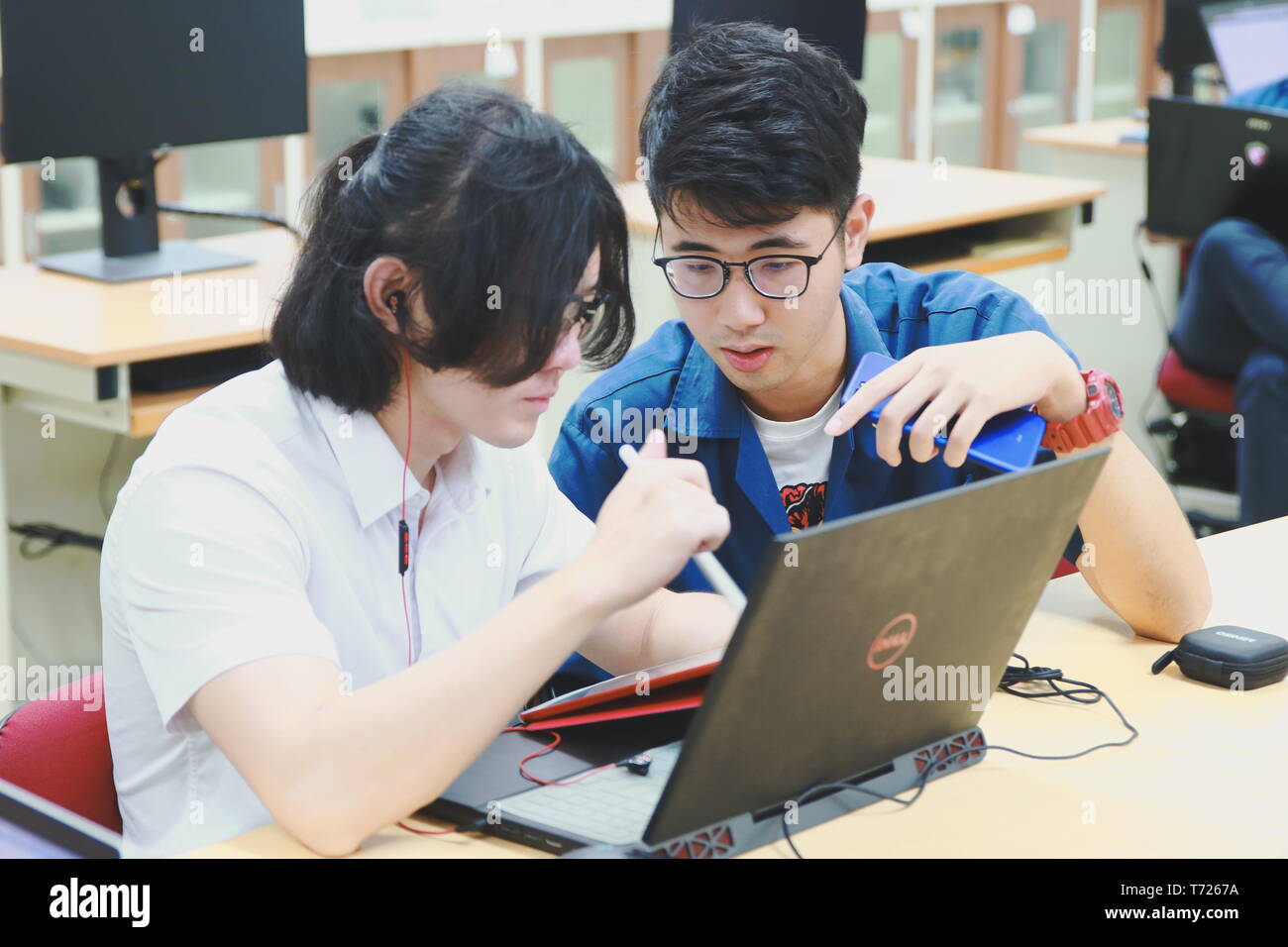 Two Chinese computer engineering student working together on a laptop in a computer programming class Stock Photo
