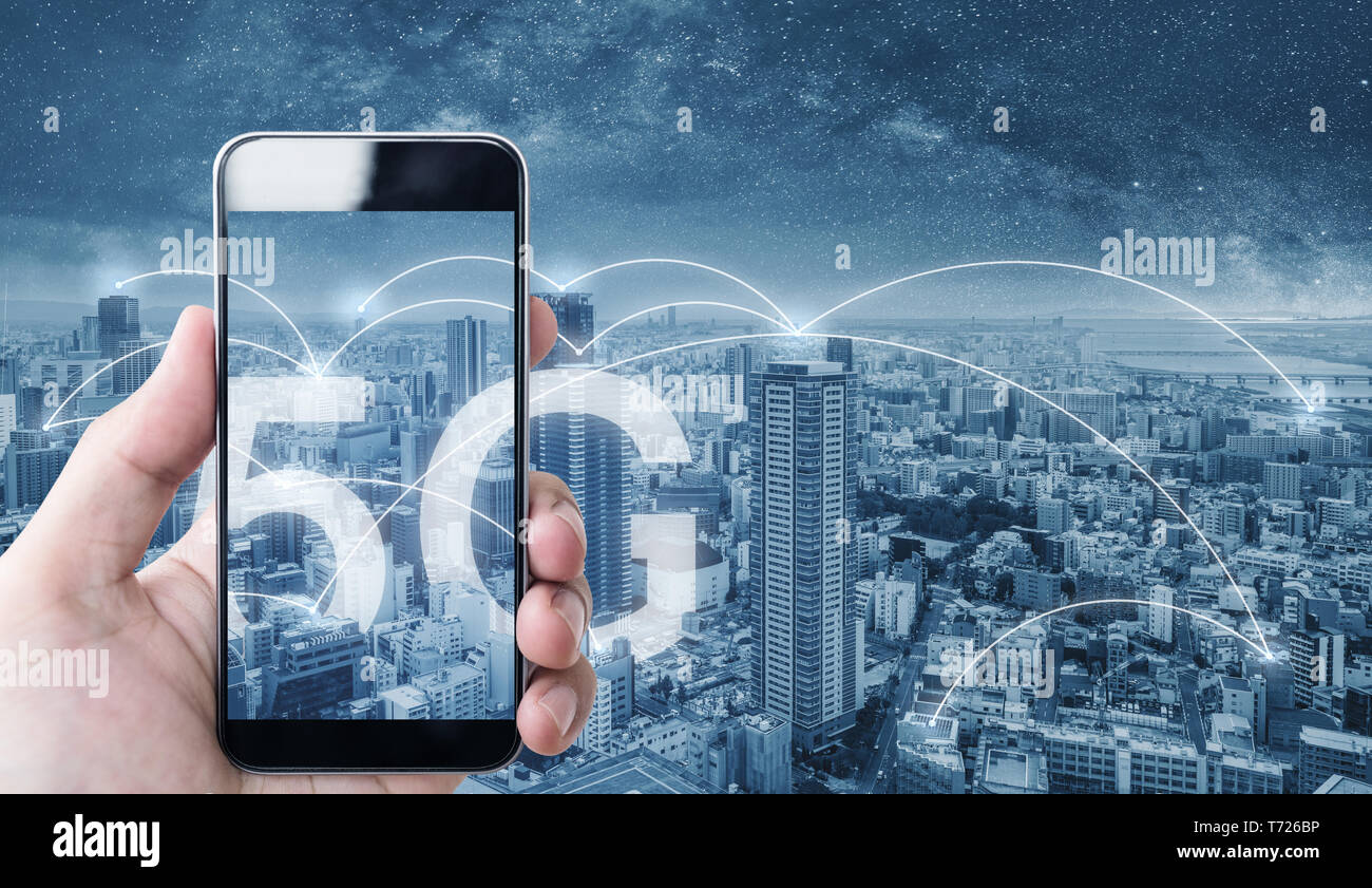Hand using mobile smart phone, and wireless network connection technology in the city, with 5g internet networking sign Stock Photo