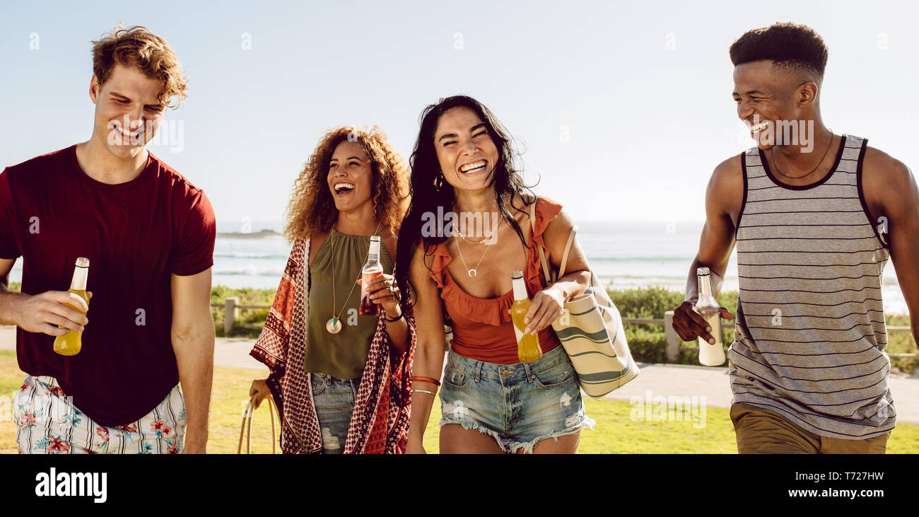 Cheerful group of men and women at walking outdoors with beers. Friends having a great time together outdoors. Stock Photo