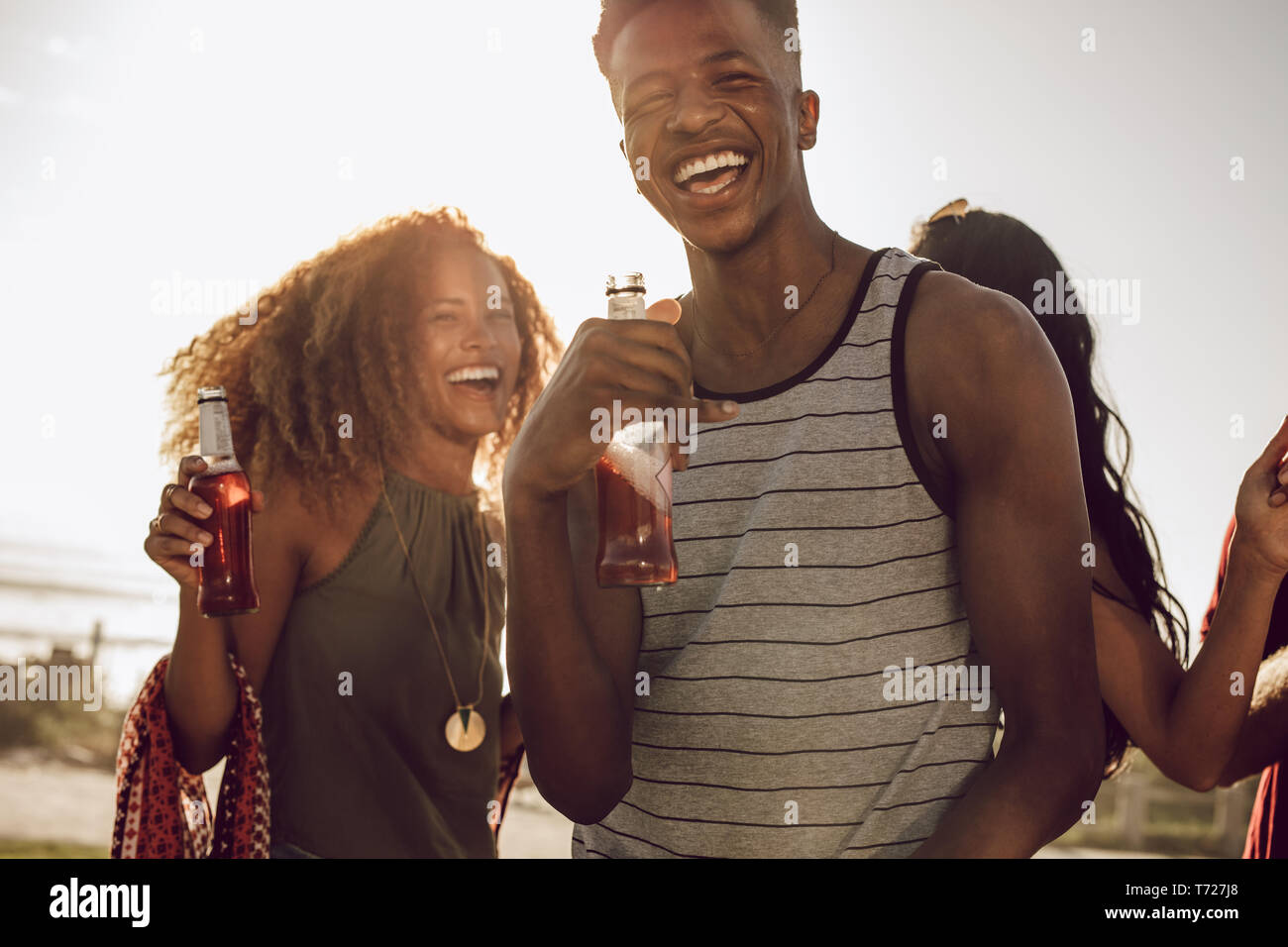 Smiling young guy with friends dancing outdoors on a sunny day. Diverse group of friends chilling out on a their weekend. Stock Photo