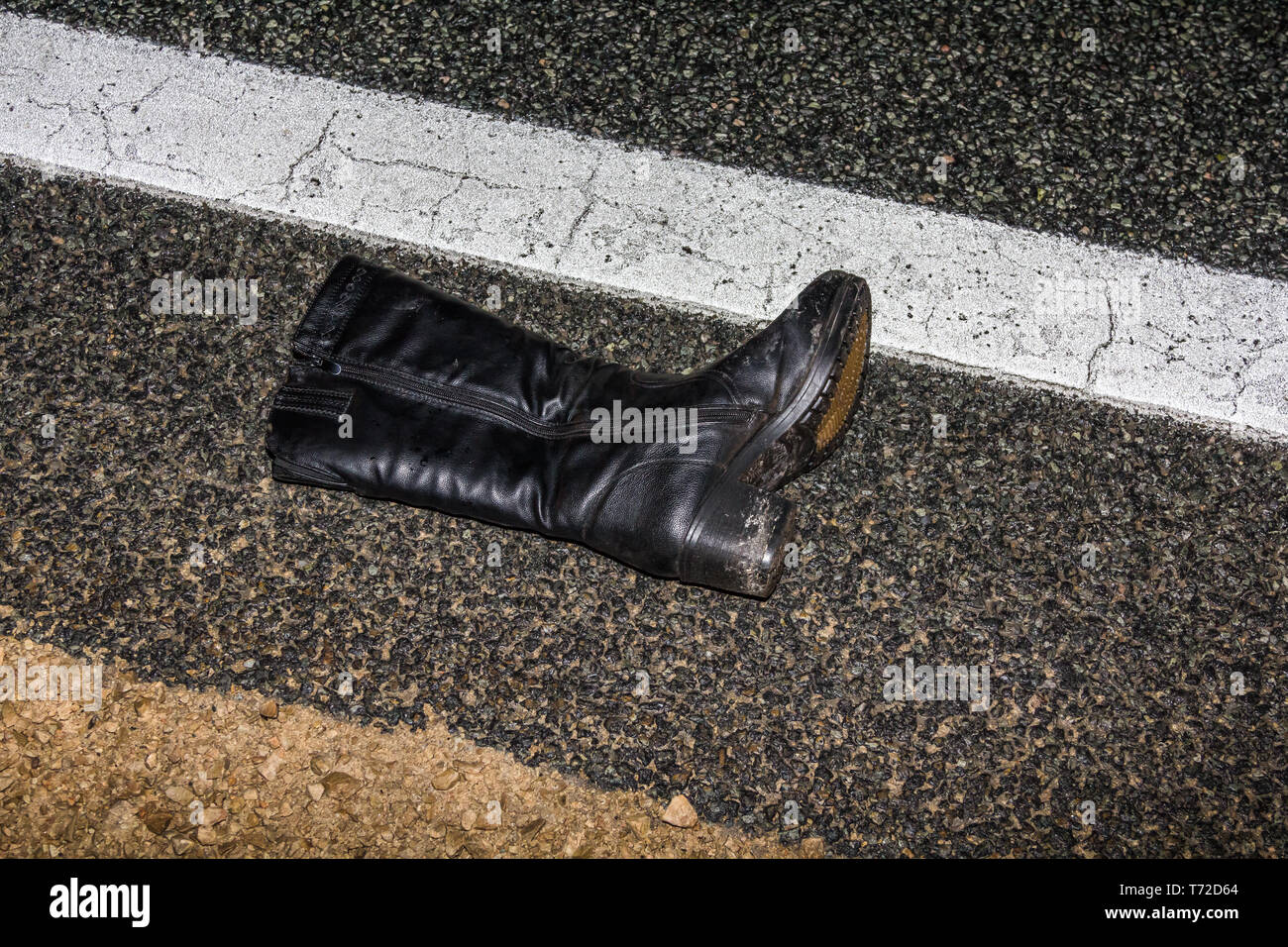 black women's boot lying on a wet asphalt road at night Stock Photo Alamy