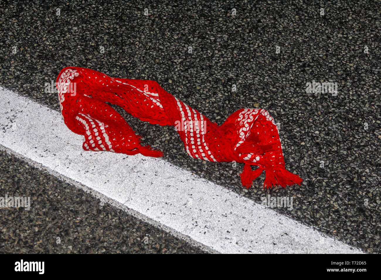 red scarf lying on a wet asphalt road at night Stock Photo