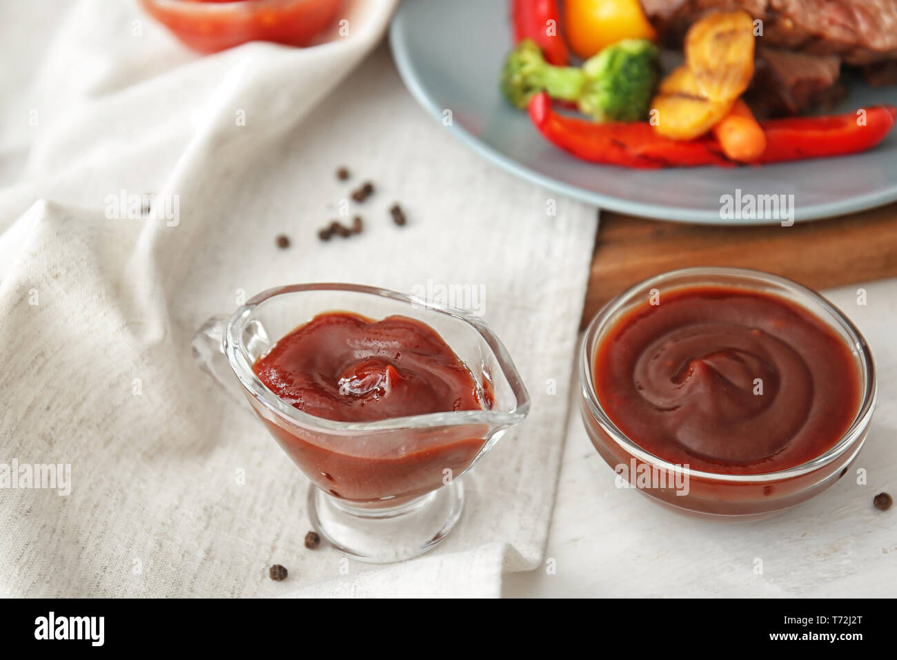 Bowl and gravy boat with barbecue sauce on table Stock Photo
