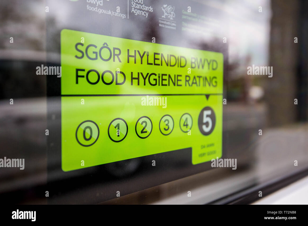 Food Hygiene Rating sticker in English and Welsh with reflections in a takeaway shop window Stock Photo