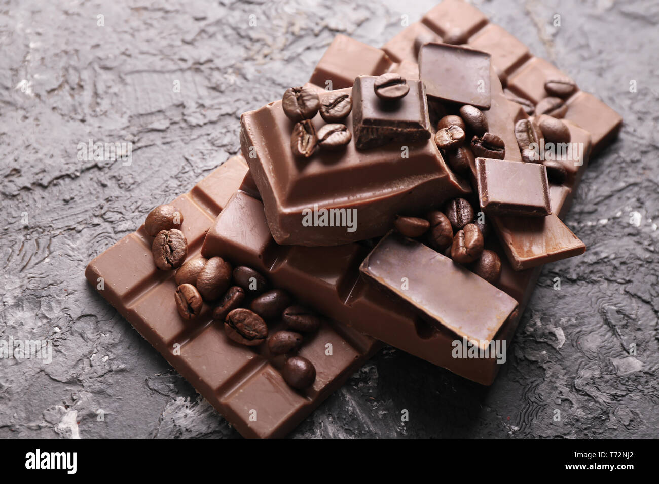 Dark and milk chocolate with coffee beans on grey textured background