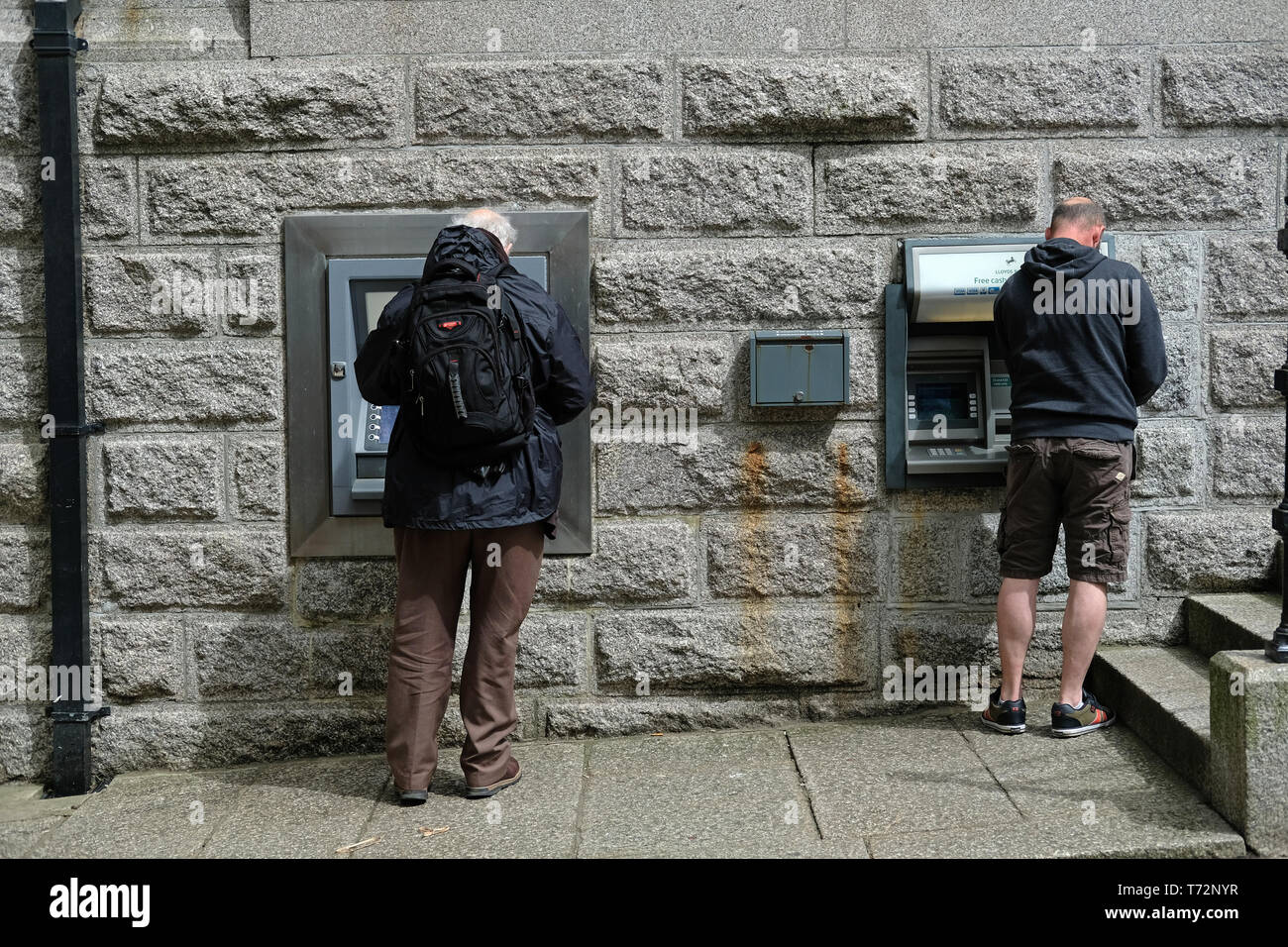 Two men using cash machines in Camborne, Cornwall, UK Stock Photo