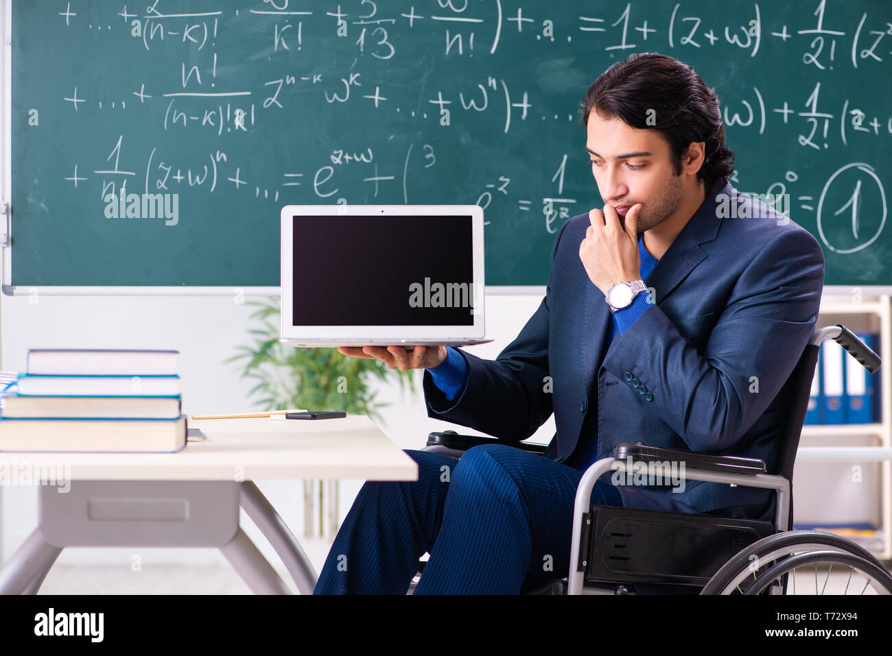 Young handsome man in wheelchair in front of chalkboard Stock Photo
