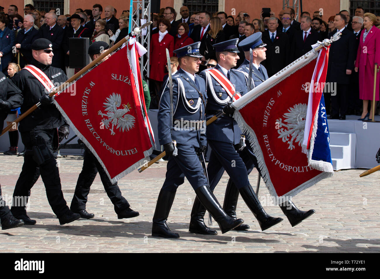 Military troops seen marching while holding flags during the occasion. Celebration of the Constitution Day, May 3 at the Castle Square. Ceremonial military parade on the occasion of the celebration. Stock Photo