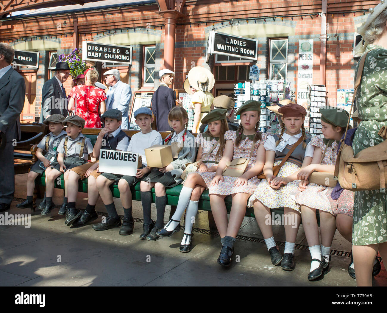 Severn Valley Railway, 1940's wartime event, Kidderminster vintage railway station. Boys & girls (evacuees) in 1940's dress sitting on bench waiting. Stock Photo