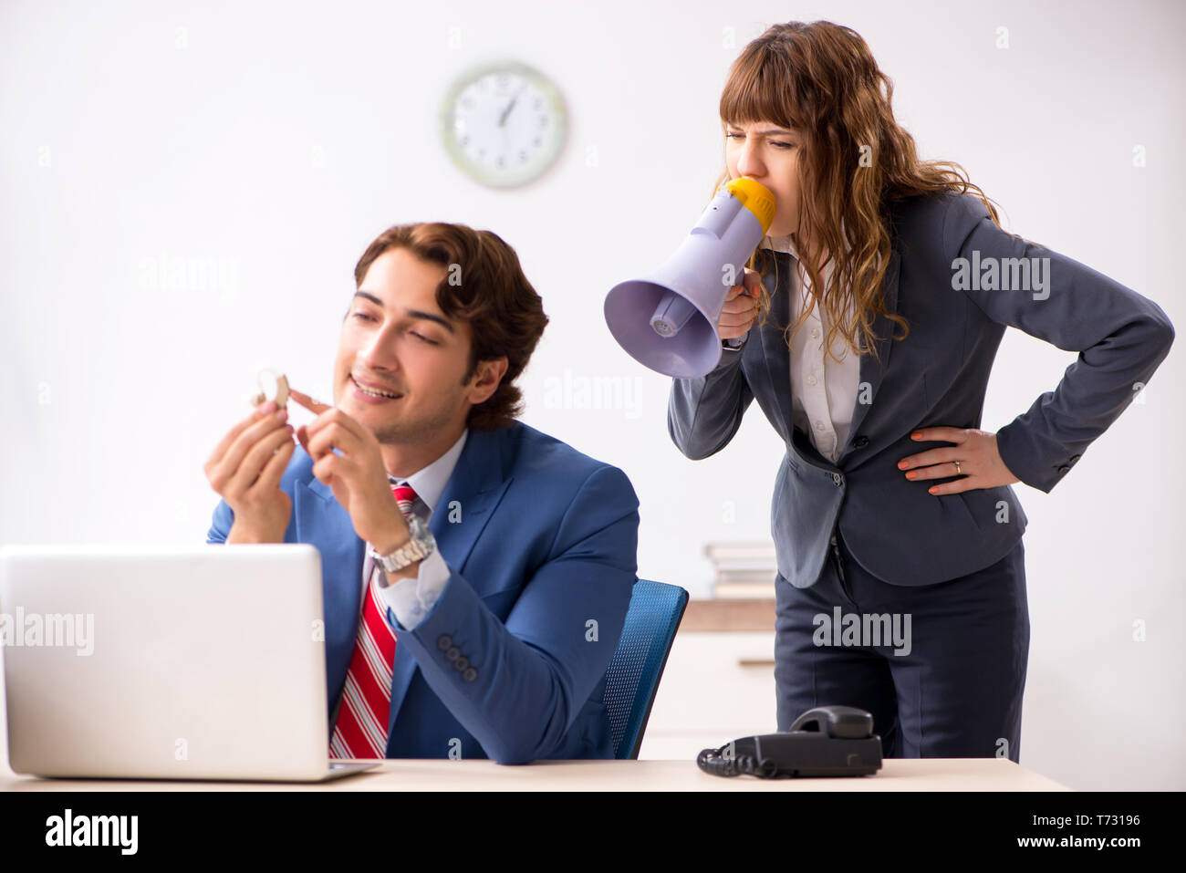 Deaf employee using hearing aid talking to boss Stock Photo