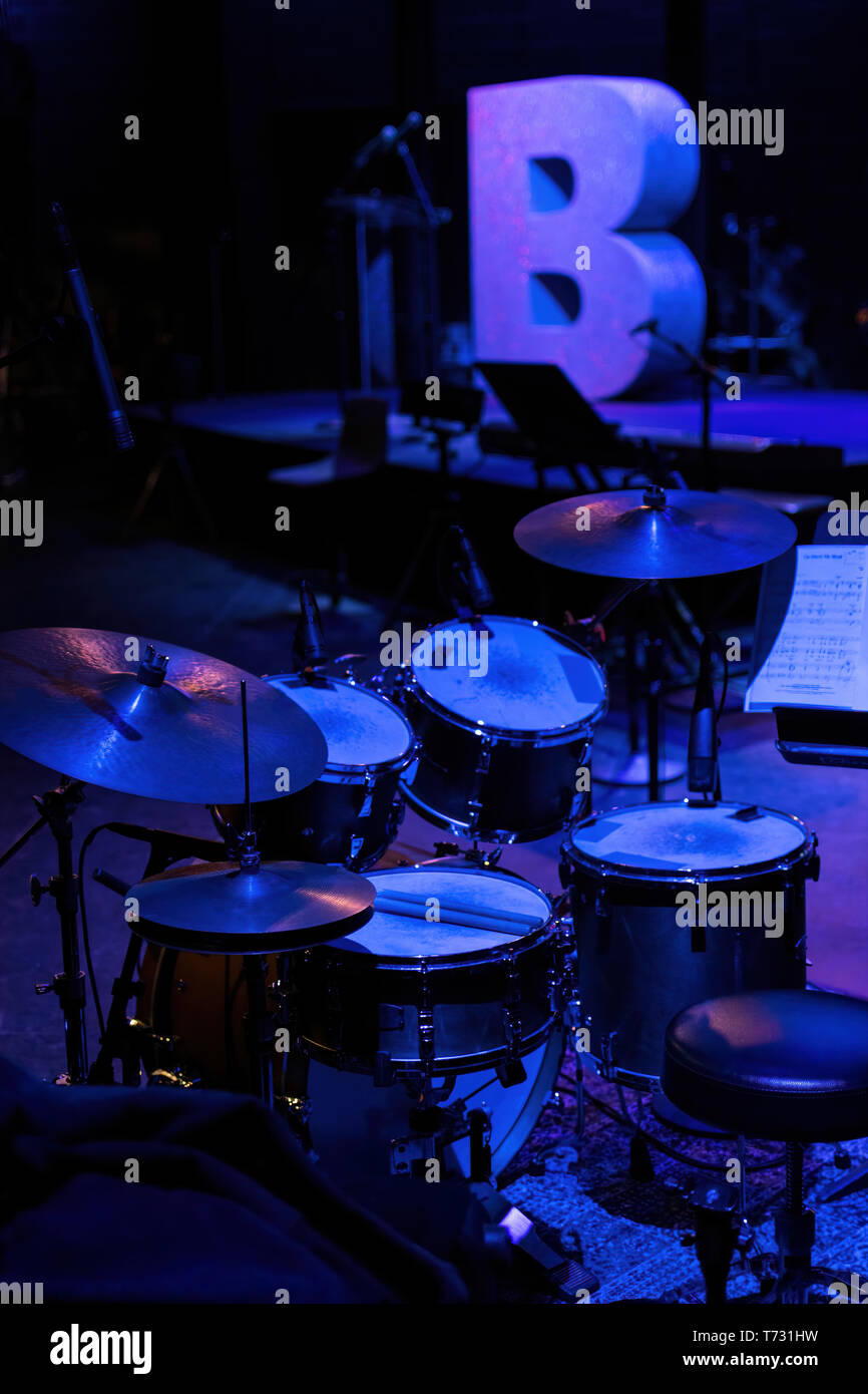 A set of drums on a stage doused in pale blue light Stock Photo