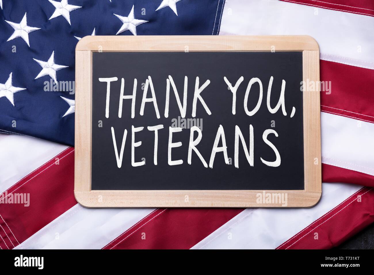 Top View Of Thank You Veterans Text Written On Slate Over American Flag Stock Photo